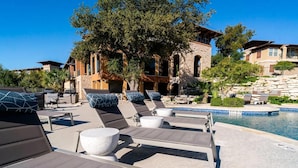A poolside area with lounge chairs and a stone building in the background. - Landing Furnished Apartments - Northwest Austin (Austin)