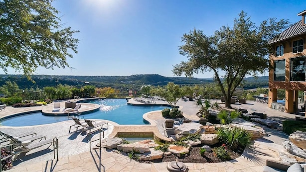 A pool area with multiple swimming pools, lounge chairs, and a view of the surrounding landscape. - Landing Furnished Apartments - Northwest Austin (Austin)