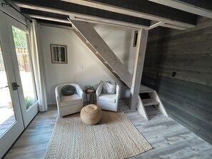 Ein modernes Interieur mit Treppe, zwei weißen Sesseln, einem kleinen Beistelltisch und einem gewebten Teppich.