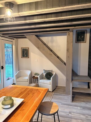 Ein modernes Interieur mit einem Holzesstisch, zwei Sesseln, einem kleinen Beistelltisch und einer Treppe.