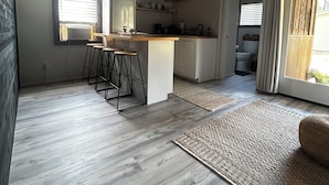 Une cuisine moderne dotée d’un îlot central, de tabourets de bar et donnant sur la salle de bain adjacente.