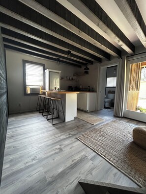 A modern kitchen with a central island, bar stools, and a view into the adjacent bathroom. - The Backyard Hideout (Mancos)