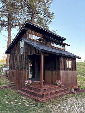 Ein rustikales, zweistöckiges Holzhaus mit einer Veranda und einem kleinen Vorgarten.