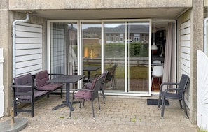 A patio with a table and chairs, a sliding glass door, and a view of a residential area. - Gorgeous apartment in Fanø with WiFi (Fanø)