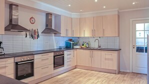 A modern kitchen with a central island, stainless steel appliances, and light wood cabinetry.