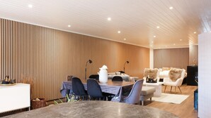 A modern dining area with a wooden wall, a round table, and contemporary chairs.