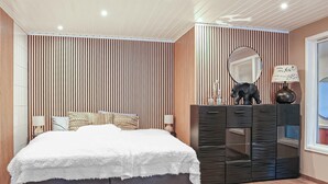 A bedroom with a bed, a dresser, a mirror, and a window.