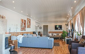 A living room with a large grey sofa, a wooden floor, and a television mounted on the wall. - Cozy home in Bokn with sauna (Bokn)