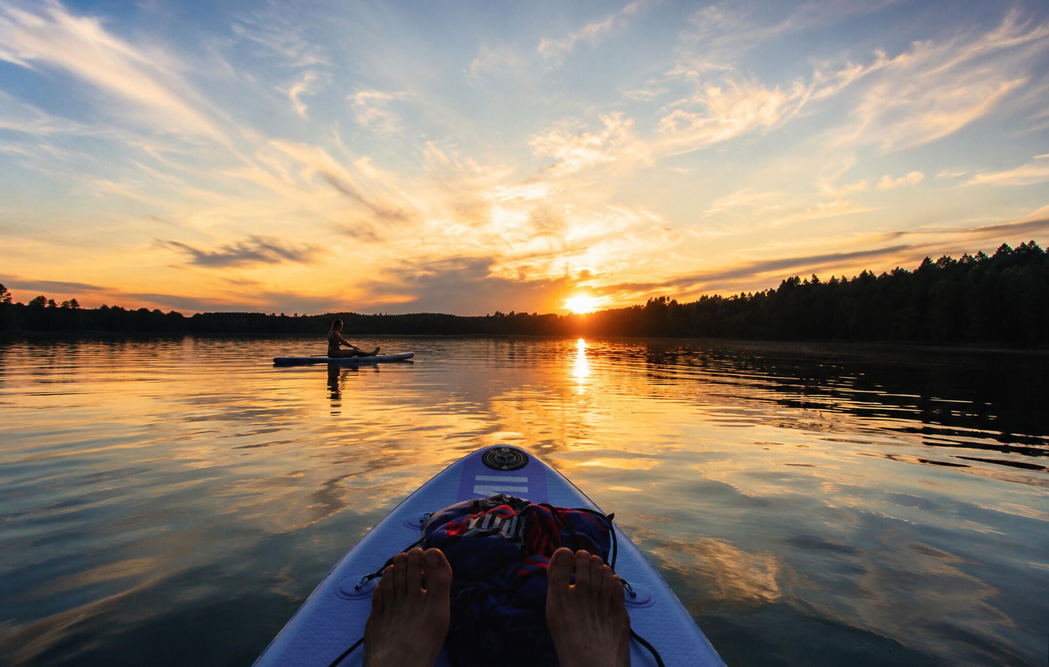A kayak on calm water with a sunset in the background.