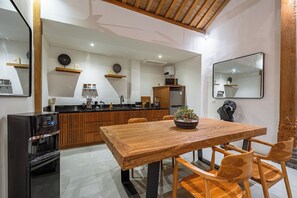 A modern kitchen with wooden cabinets, a built-in stove, and a dining area with a wooden table and chairs.