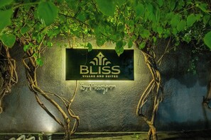 Une enseigne pour « BLISS Villas and Suites », avec un mur texturé et des plantes grimpantes.
