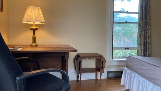 A room with a desk, chair, and a bed. There is a window with a view of trees. - Charming East View overlooks College Green Park (Iowa City)