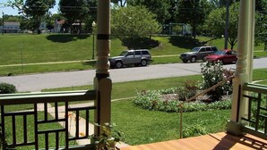 A porch with a view of a street, a garden, and a residential area. - Charming East View overlooks College Green Park (Iowa City)