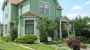 A two-story house with a green exterior, a front porch, and a garden. - Charming East View overlooks College Green Park (Iowa City)