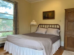 Ein Schlafzimmer mit einem Bett, einem Fenster, einer Lampe und einem Bild an der Wand.