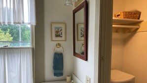 A bathroom with a white sink, a mirror, a towel rack, and a framed picture on the wall. - Charming East View overlooks College Green Park (Iowa City)