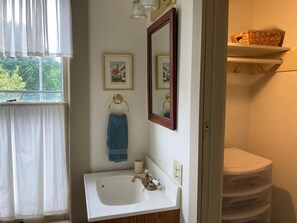 Ein Badezimmer mit einem weißen Waschbecken, einem Spiegel, einem Handtuchhalter und einem gerahmten Bild an der Wand.