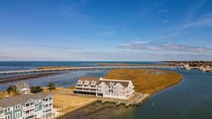 A coastal property with a large house, a pier, and a bridge in the background. - Gorgeous Bay Views - No Egrets by Seaside Vacations! (Chincoteague)