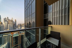 Ein Balkon mit Blick auf die Stadt, ein Sessel und ein Tisch.