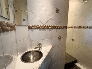 Ein Badezimmer mit Waschbecken, Spiegel und gefliesten Wänden.