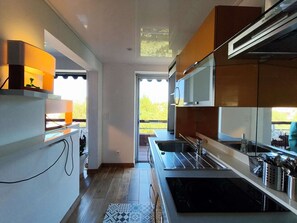 A modern kitchen with a built-in oven, a sink, and a window overlooking a deck. - TOIT-TERRASSE D'EXCEPTION  et  VUE MER PANORAMIQUE A ST TROPEZ (ST TROPEZ)