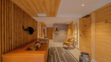 A wooden interior with a bench, a chair, and a large metal container.
