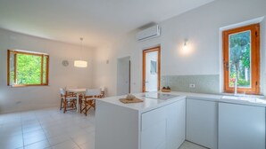 Una cucina moderna con mobili bianchi, un'isola centrale e una zona pranzo con tavolo e sedie.