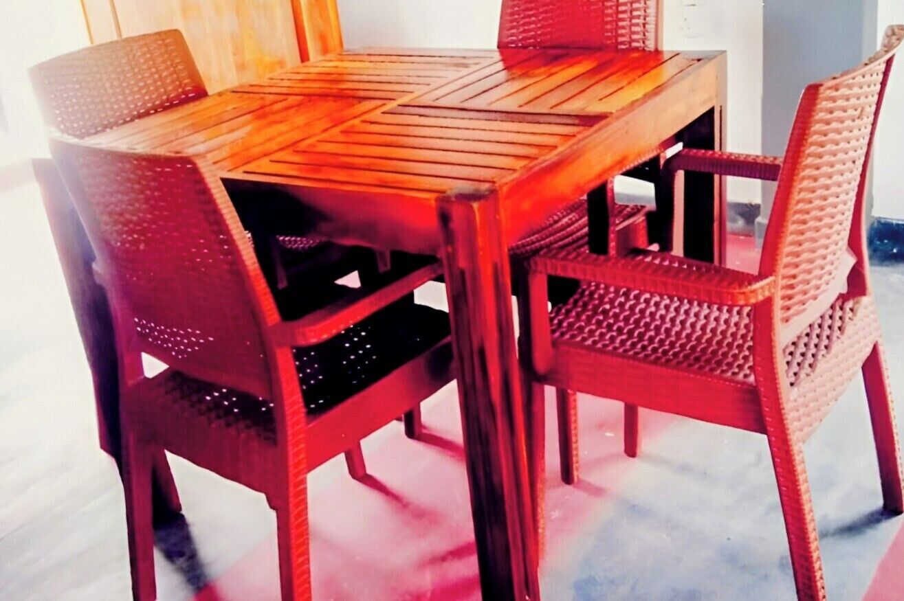 Une table en bois, accompagnée de quatre chaises, chacune dotée d’un siège et d’un dossier en osier tressé.