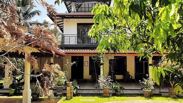 A two-story house with a covered porch, potted plants, and a paved pathway. - Habarana Guest House  (Habarana)