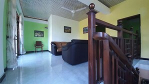 A living room with a sofa, a chair, a staircase, and a ceiling fan. - Habarana Guest House  (Habarana)