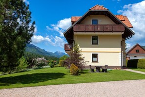 A two-story house with a balcony, a paved driveway, and a well-maintained lawn.