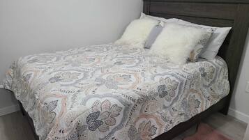 Ein Bett mit einem gemusterten Überwurf, zwei Kissen und einem Holzkopfteil.