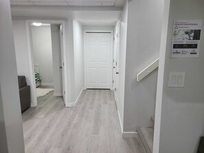 Un passadís amb una porta blanca, una escala i un senyal fixat a la paret.