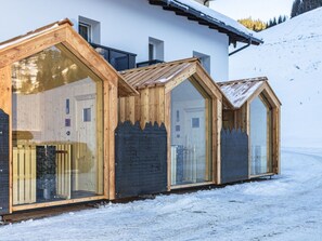 Een rij houten blokhutten met grote ramen, op de achtergrond sneeuw.