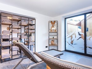 Een moderne badkamer met een douchecabine van glas, een ingebouwde handdoekhouder en een rieten stoel.