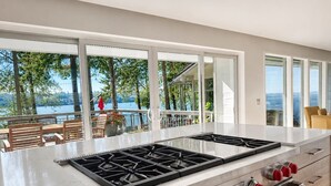 A kitchen with a large island, a stove, and a view of the outdoors.