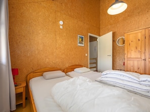 A bedroom with a wooden bunk bed, a wooden wardrobe, a small bedside table, and a door leading to a bathroom. - Holiday home with 3 bedrooms near the sea (Westende)