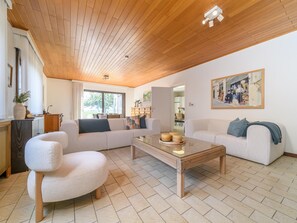 Ein modernes Wohnzimmer mit Holzboden, einem Glastisch und einem großen Fenster.