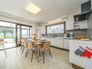 A modern kitchen with a dining area, large windows, and a view of the outdoors. - Holiday home Villa Robert (Veurne)