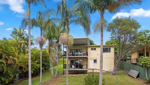 A two-story building with a balcony, surrounded by palm trees and a well-maintained lawn. - Waterfront Creek Access, Large Entertaining Deck, Minutes to Beaches (Hyland Park)