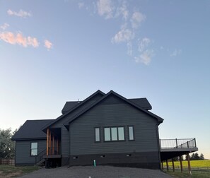 A modern two-story house with a dark exterior, a covered porch, and a fenced yard.
