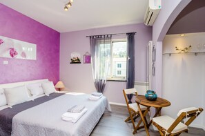 Ein Schlafzimmer mit Bett, Nachttisch, Sessel und einem kleinen Tisch mit einer Vase.