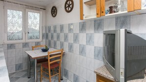 Una cucina con tavolo, sedie, televisore e mobili.