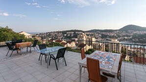Una terrazza con tavoli e sedie, che offre vista su un paesaggio urbano con edifici e una collina.