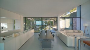 Cozinha moderna com uma mesa de jantar comprida, um sofá e vista para um jardim.