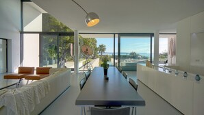 Cozinha moderna com uma mesa de jantar comprida, uma janela ampla com vista e um espaço de estar acolhedor.