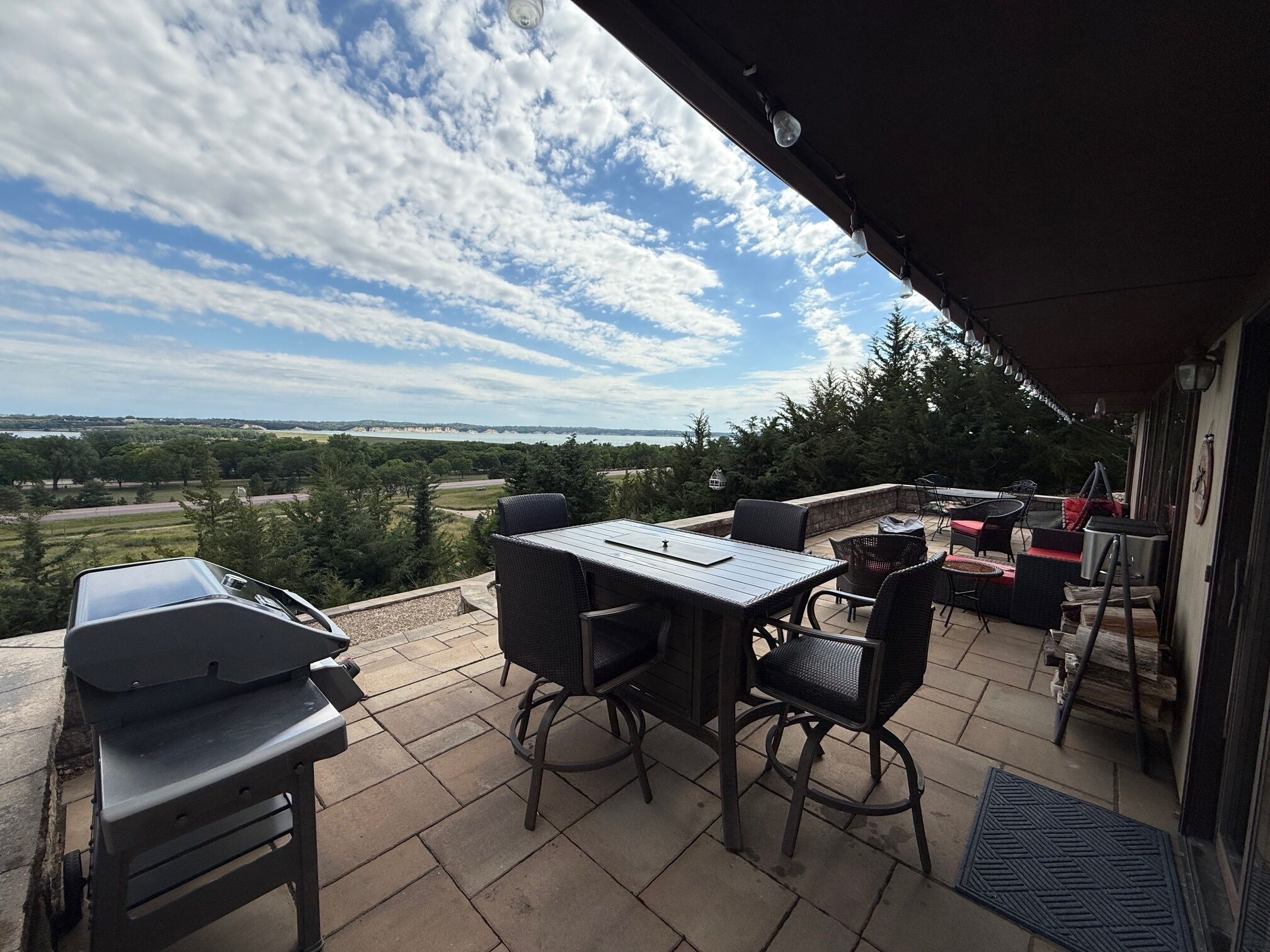 Une terrasse extérieure avec une table et des chaises, un barbecue et une vue sur le paysage.