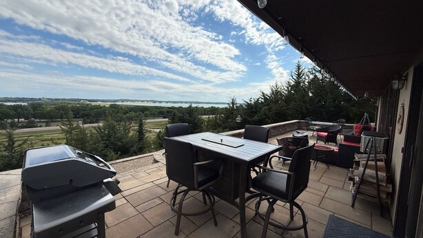 Un patio al aire libre con una mesa y sillas, una parrilla y vistas del paisaje.