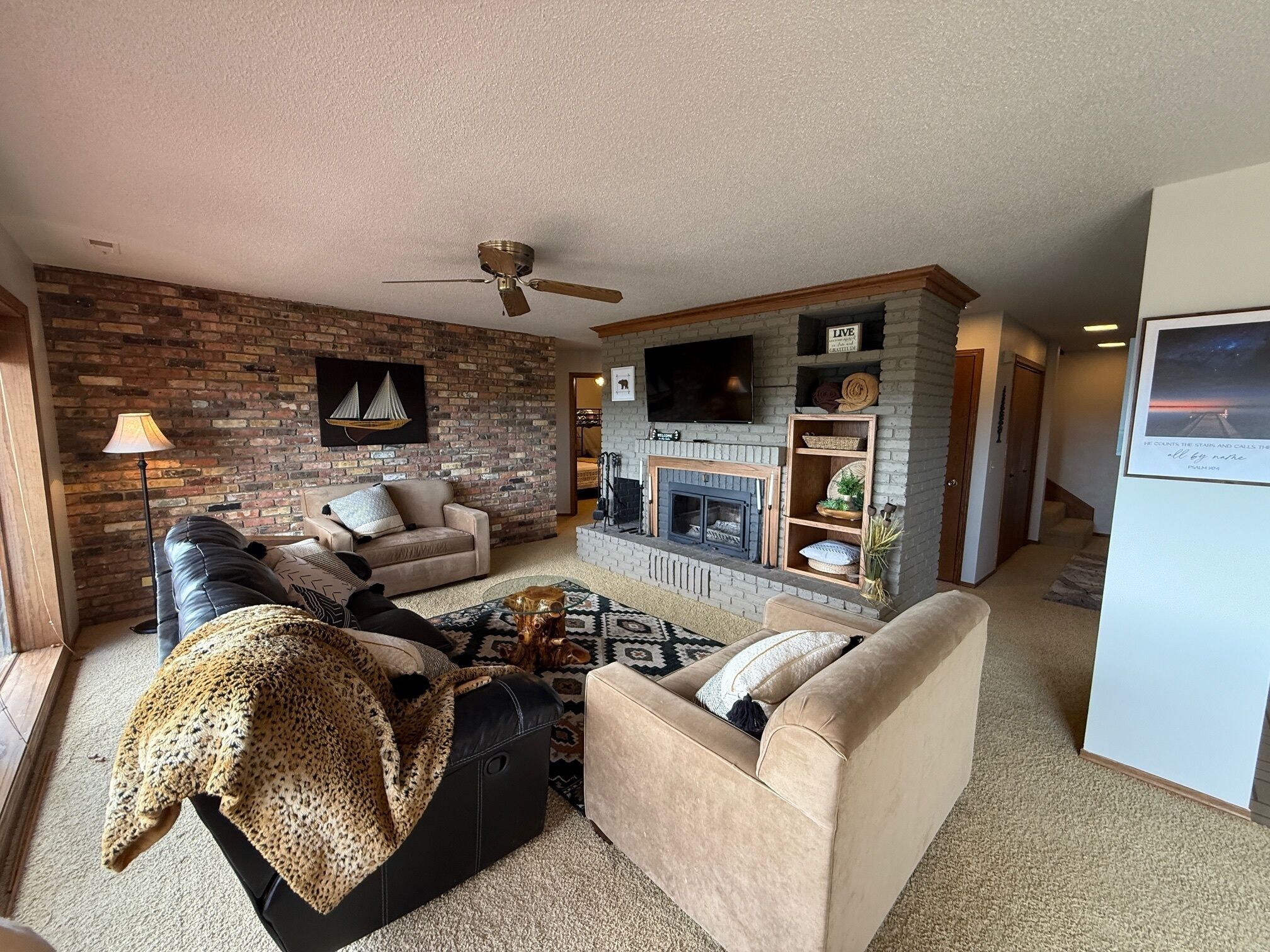 A living room with a fireplace, a sofa, a coffee table, and a TV mounted on the wall.