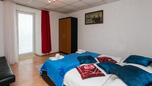 Quarto com cama, guarda-roupa, um quadro e janela com cortinas.